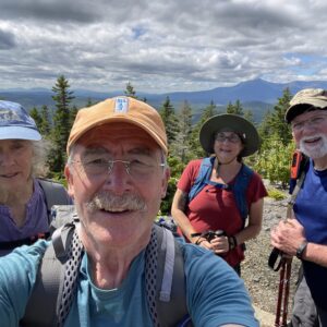 4 smiling people at the top of a mountain