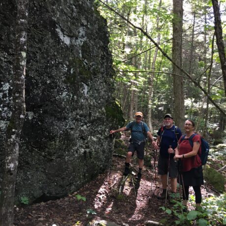 Hikers near a house sized boulder