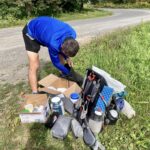 A hiker packing a backpack with a lot of gear