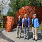 Three women in front of the sculpture